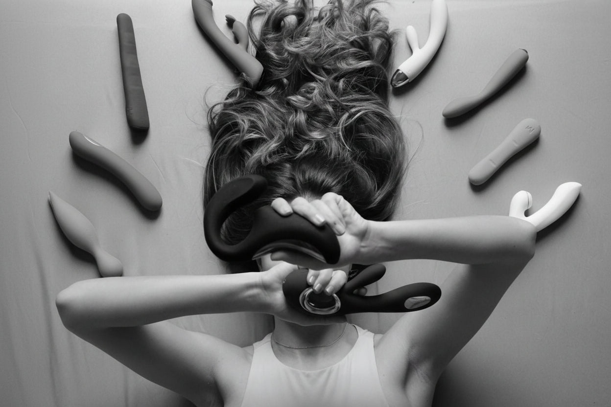 Woman holding a black hair tool with colorful tools scattered around on a gray background