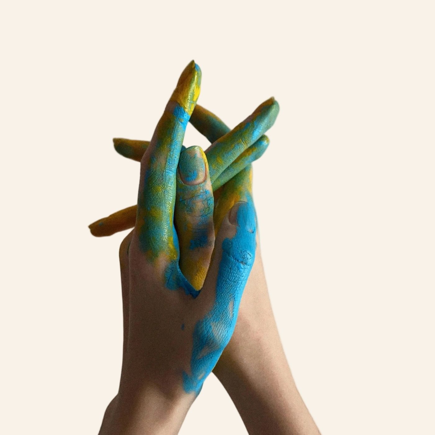 Hands with blue and green painted nails against a beige background