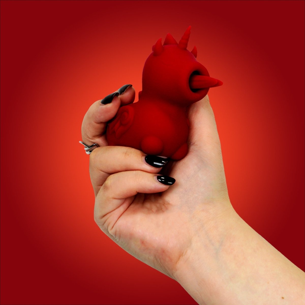 Hand holding the red Unihorn Blaze Diablo clitoral vibrator
