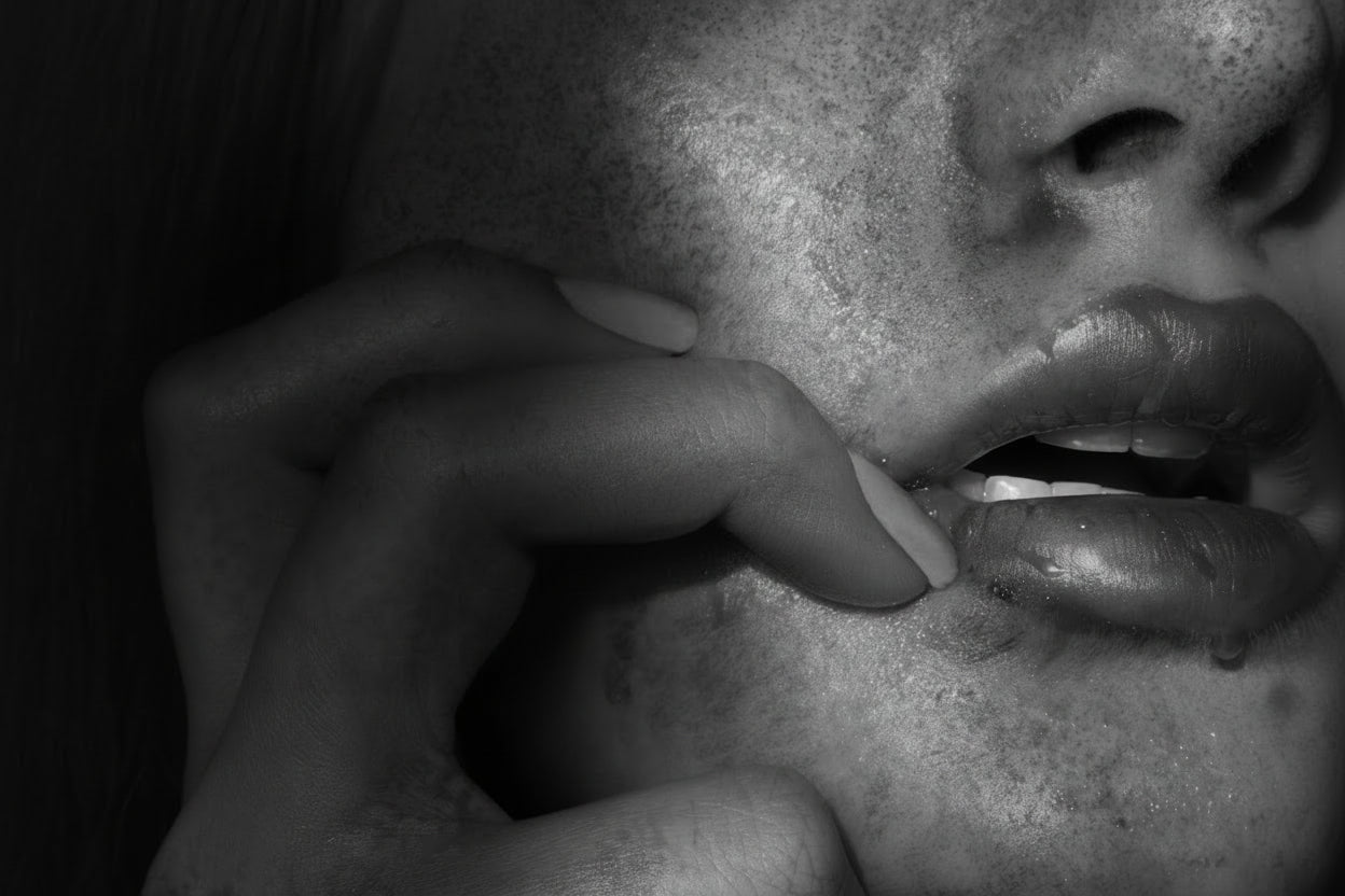 Close-up of a person's mouth with a hand touching the skin around it.
