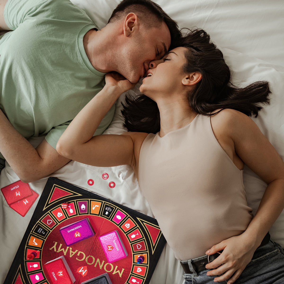 Couple kissing in bed while playing the Monogamy board game