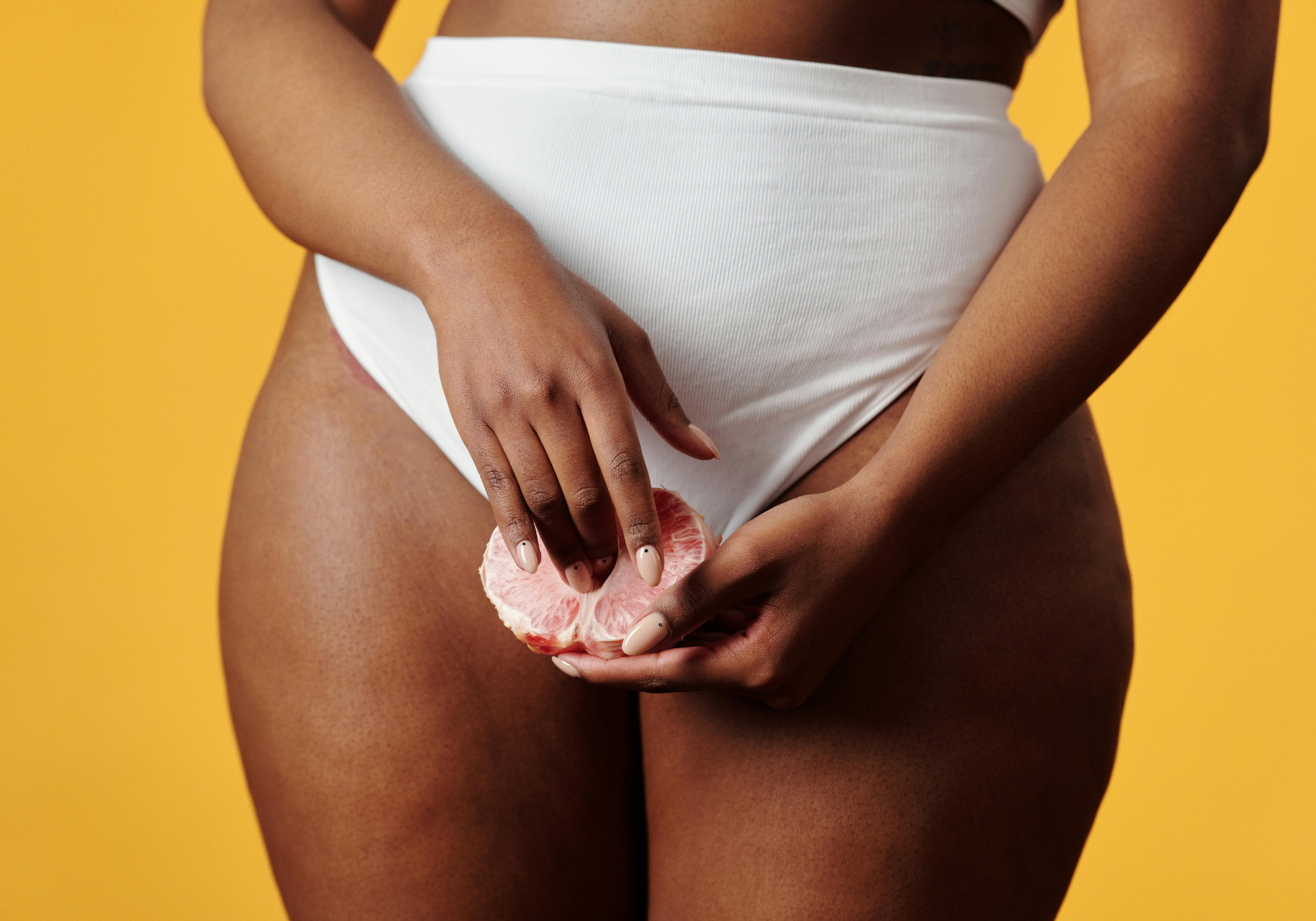 Person holding a pink object against a yellow background