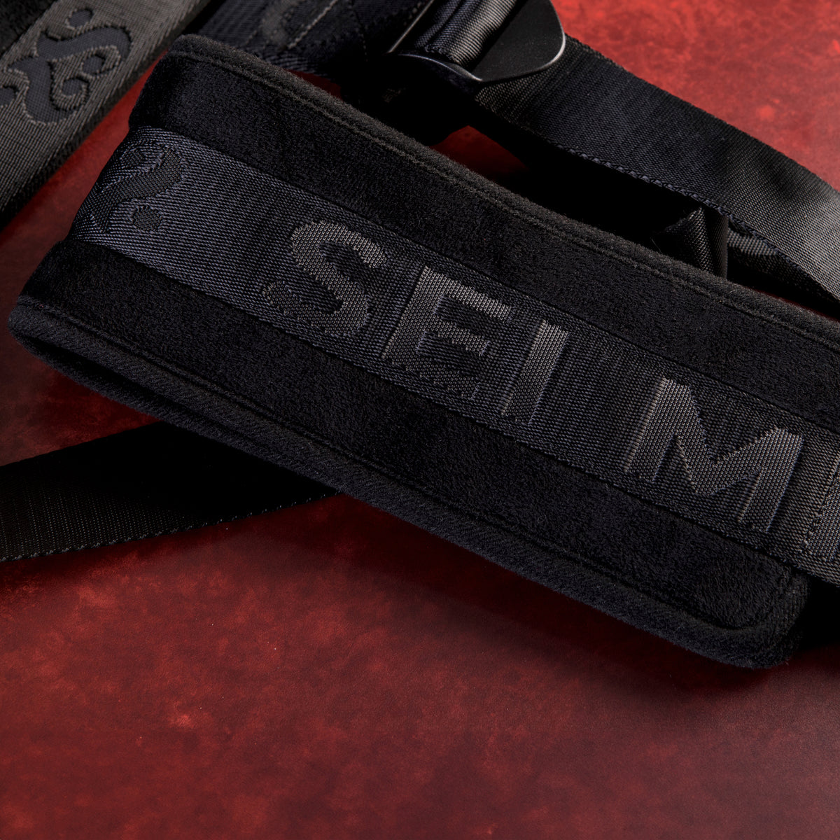 Detail of the embossed Sei Mio logo on the black padded seat of the Behind Closed Doors swing