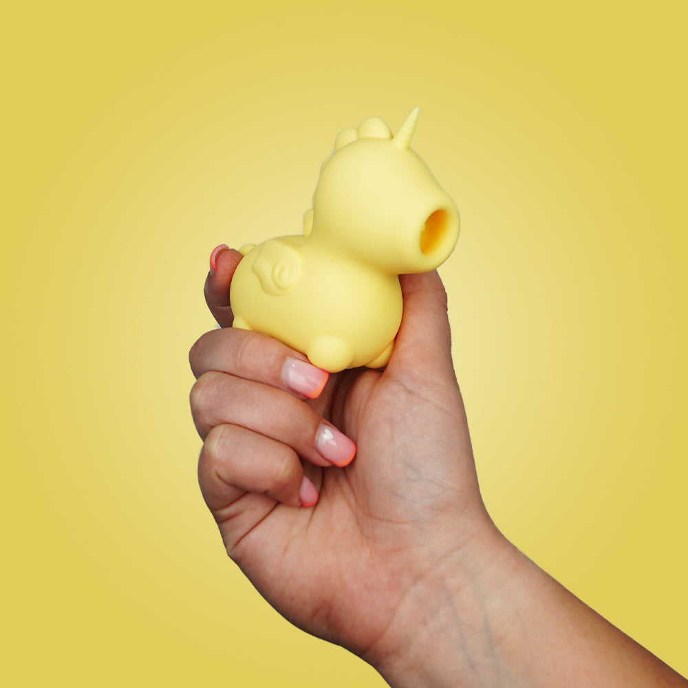 Hand holding the yellow Unihorn Bean Blossom clitoral vibrator