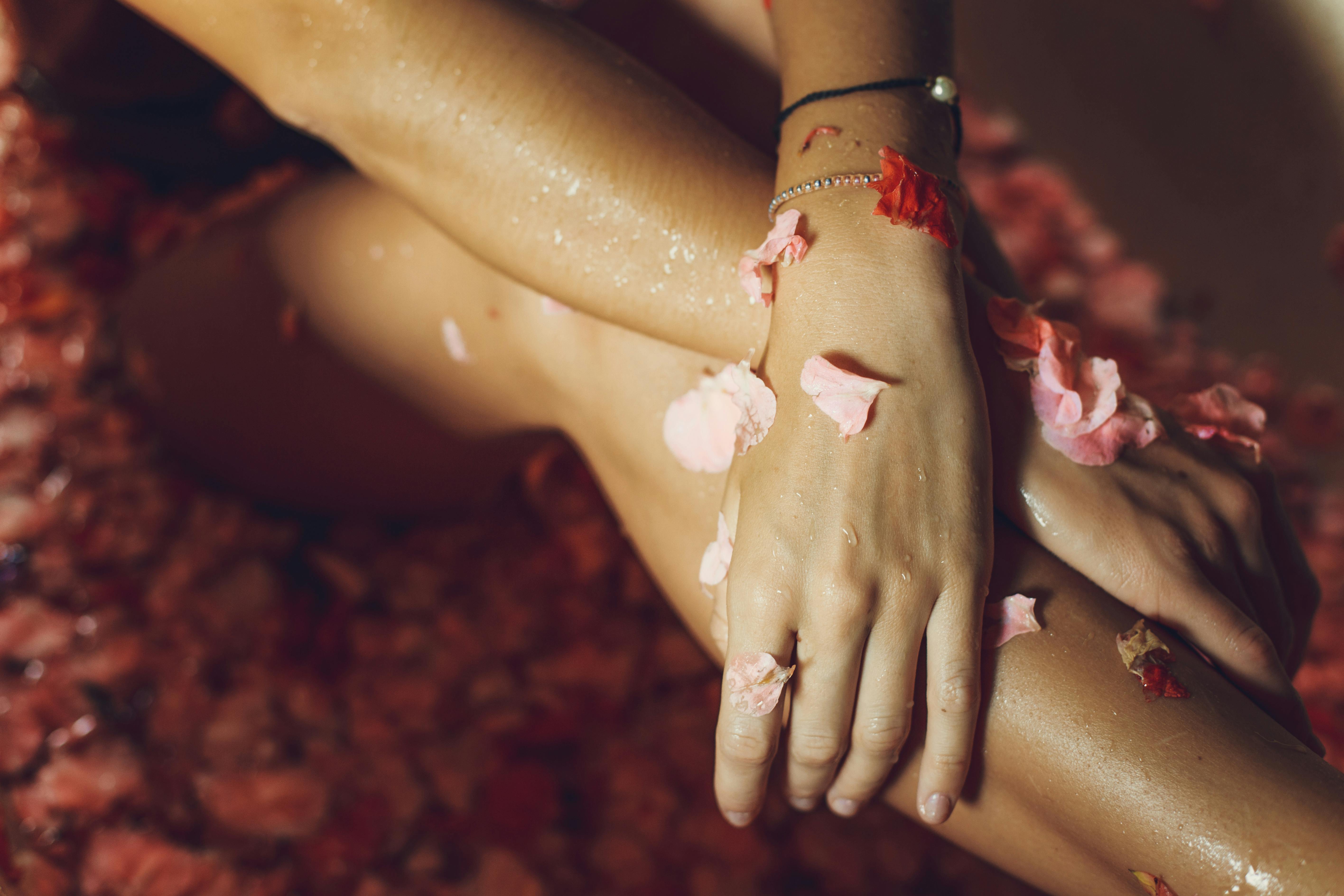 Close-up of hands with pink petals on a textured surface