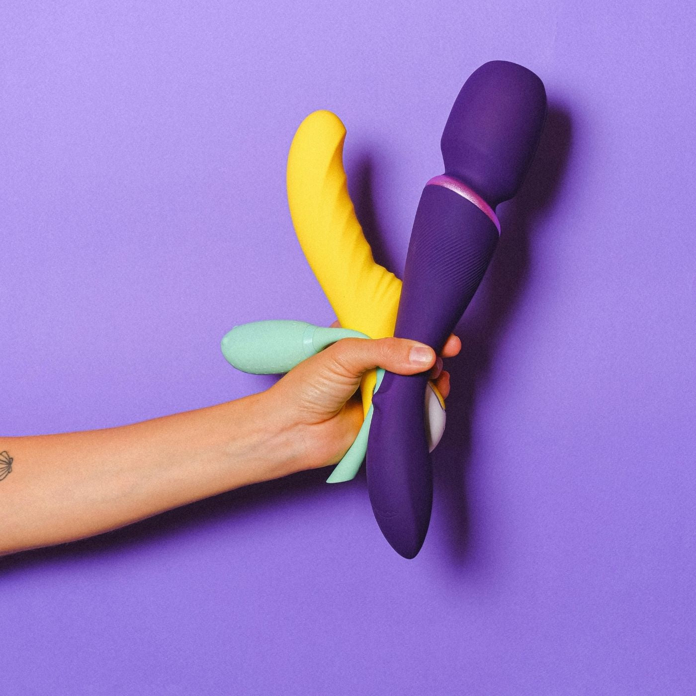Hand holding a purple and yellow toy against a purple background