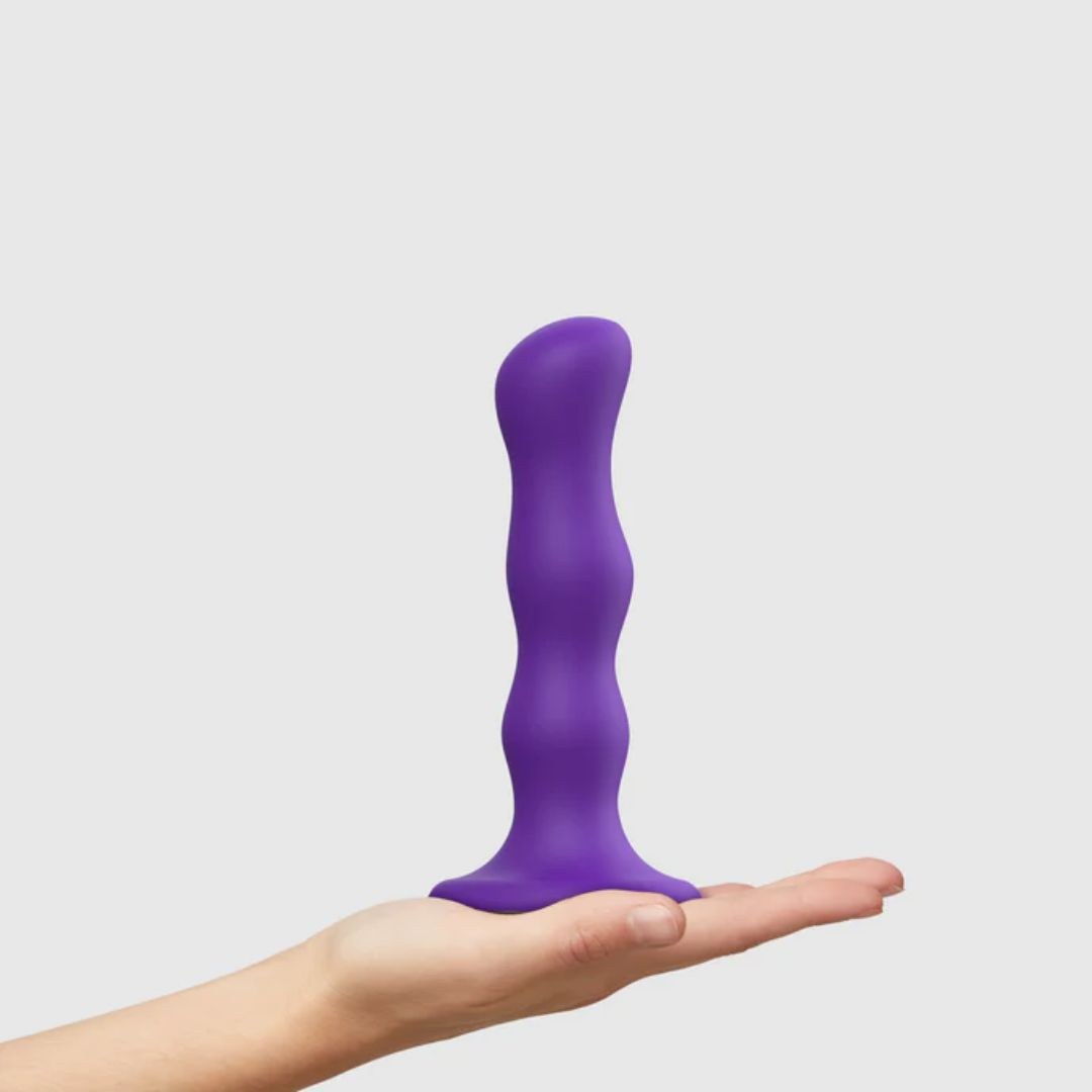 Strap On Me Geisha Balls Dildo in Purple, standing on a hand