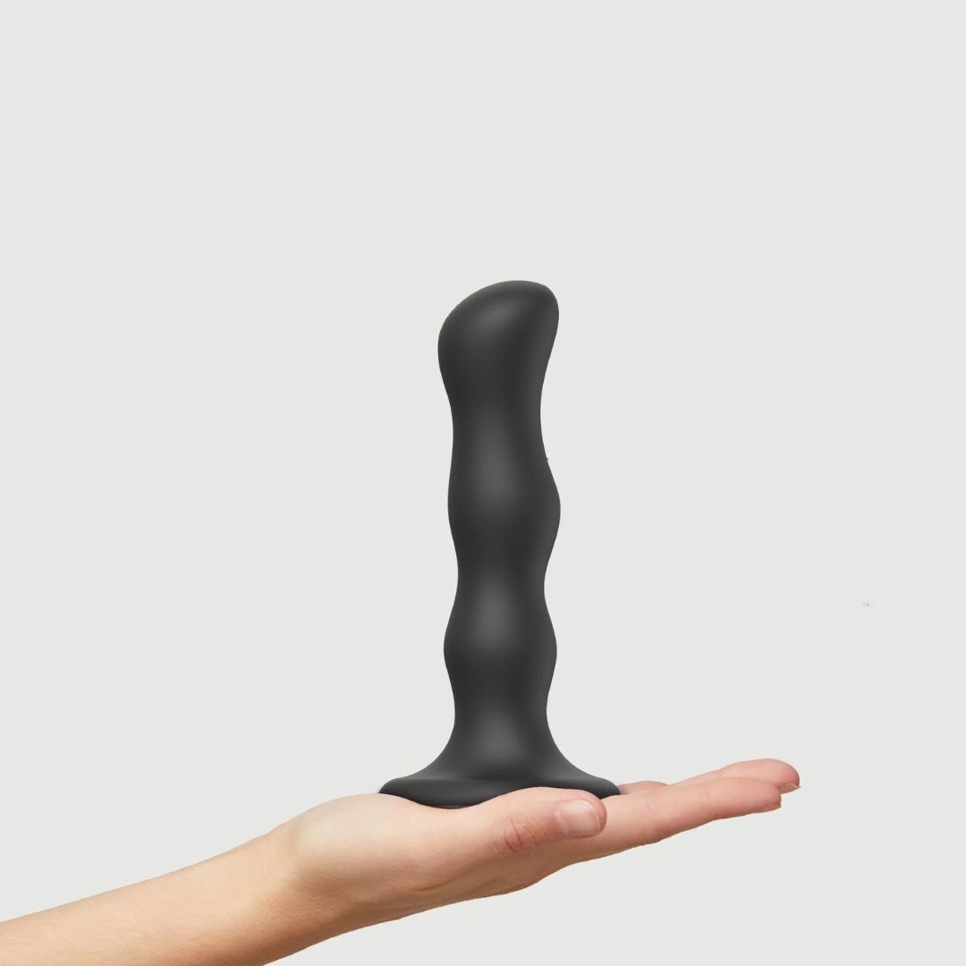 Strap On Me Geisha Balls Dildo in Black, standing on a hand