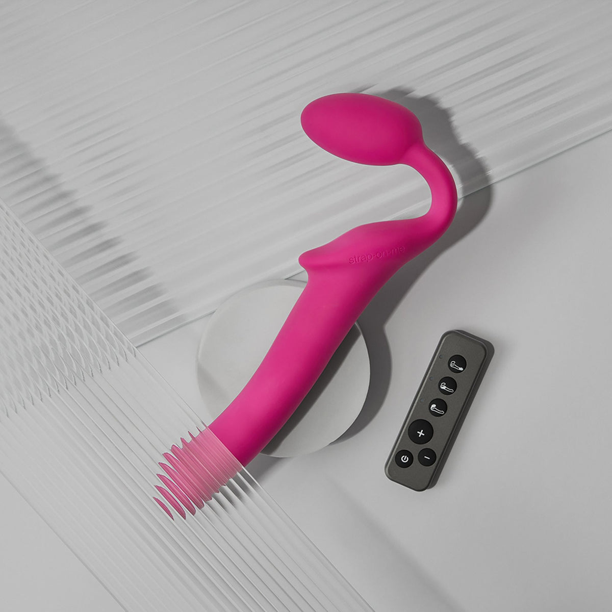 Strap On Me Vibrating Bendable Strap-On in Fuchsia, with its remote control