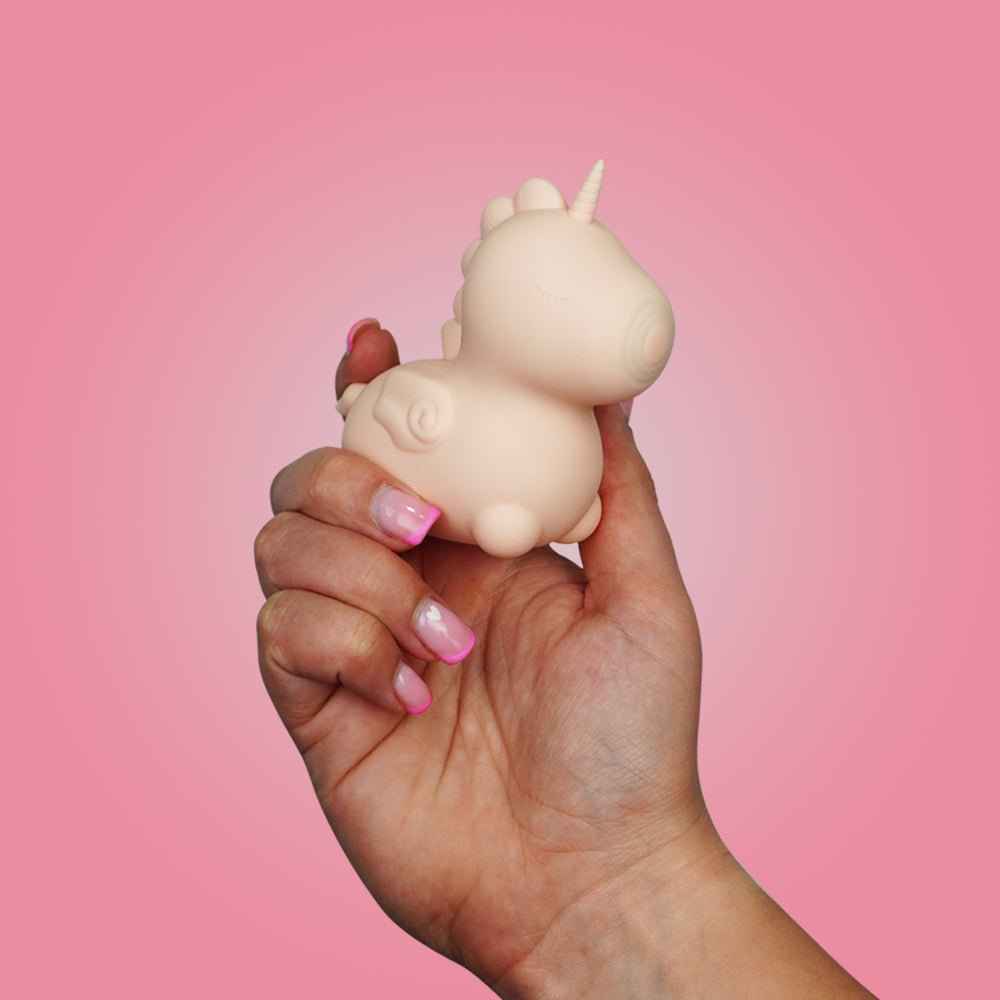 Hand holding the pink Unihorn Heart Throb clitoral vibrator